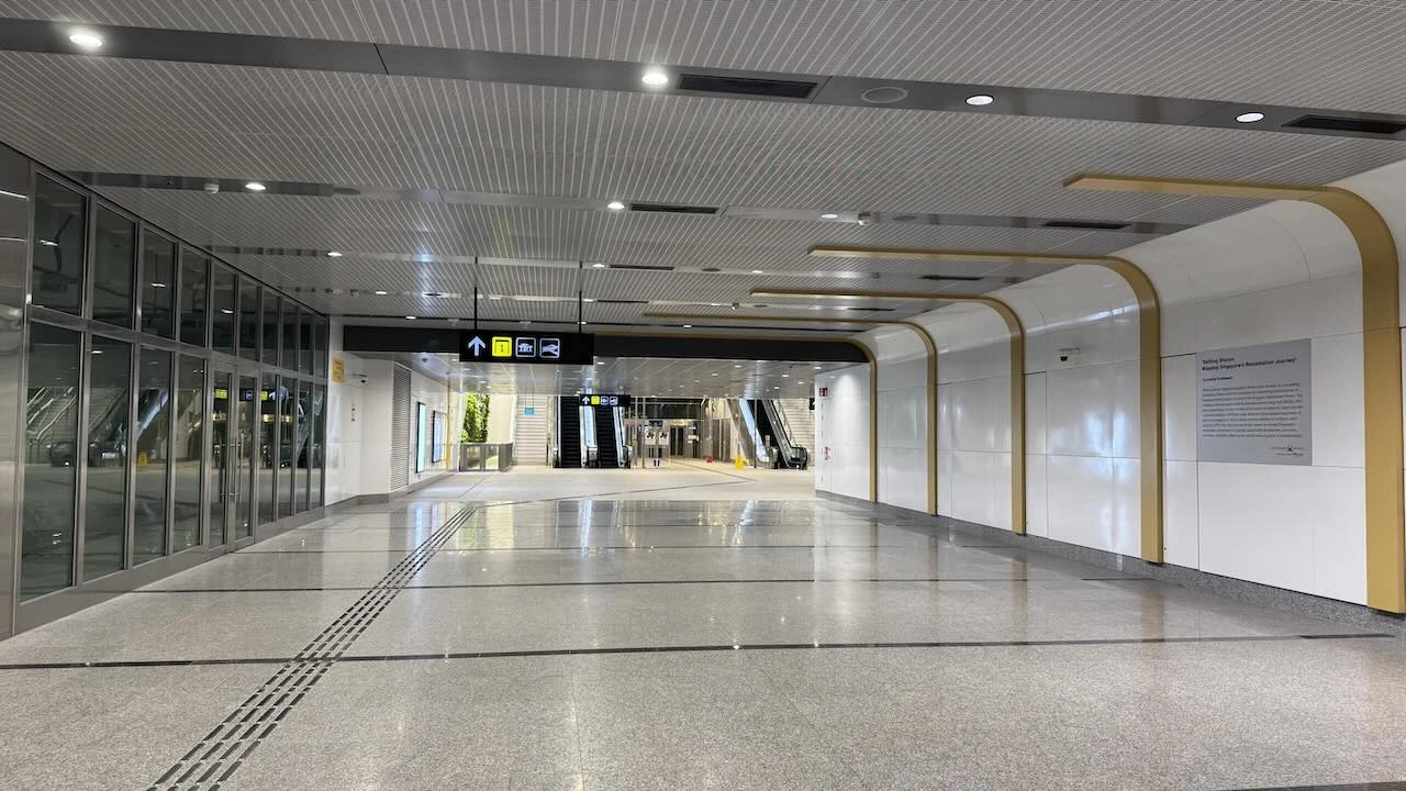 Der MRT-Bahnhof "Garden by the Bay", ein weiter Gang, sehr hell, niemand ist zu sehen, im Hintergrund eine Rolltreppe.